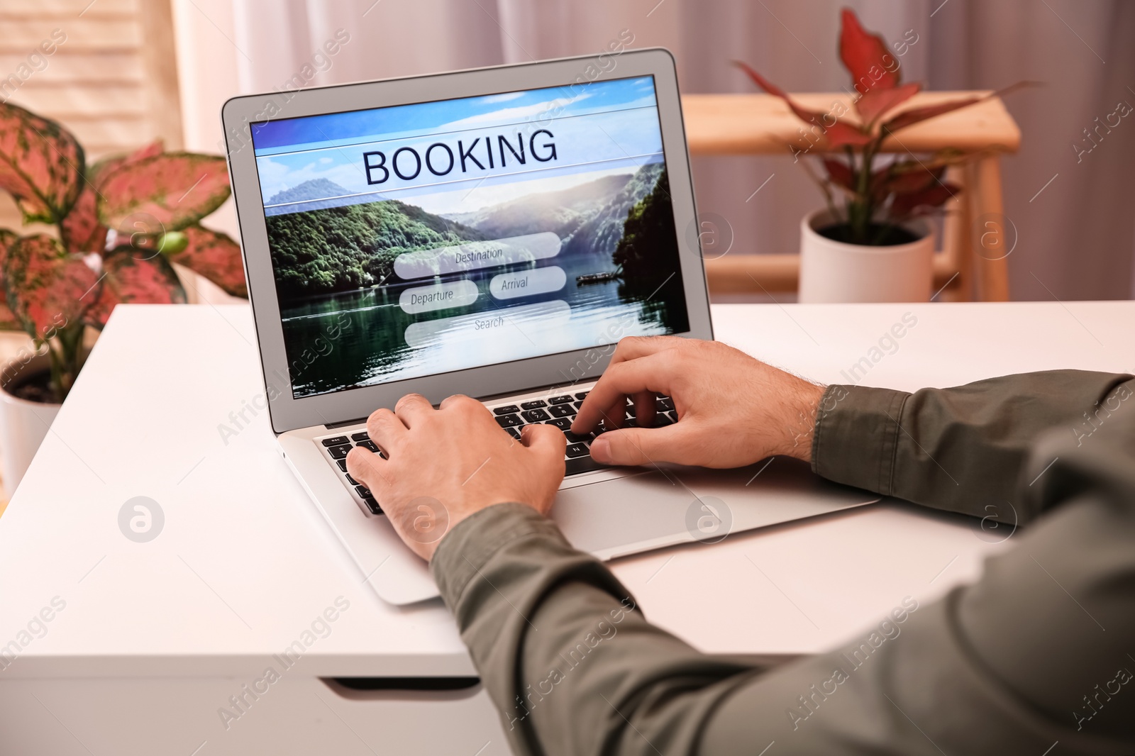 Photo of Man with laptop booking tickets online at white table, closeup. Travel agency concept