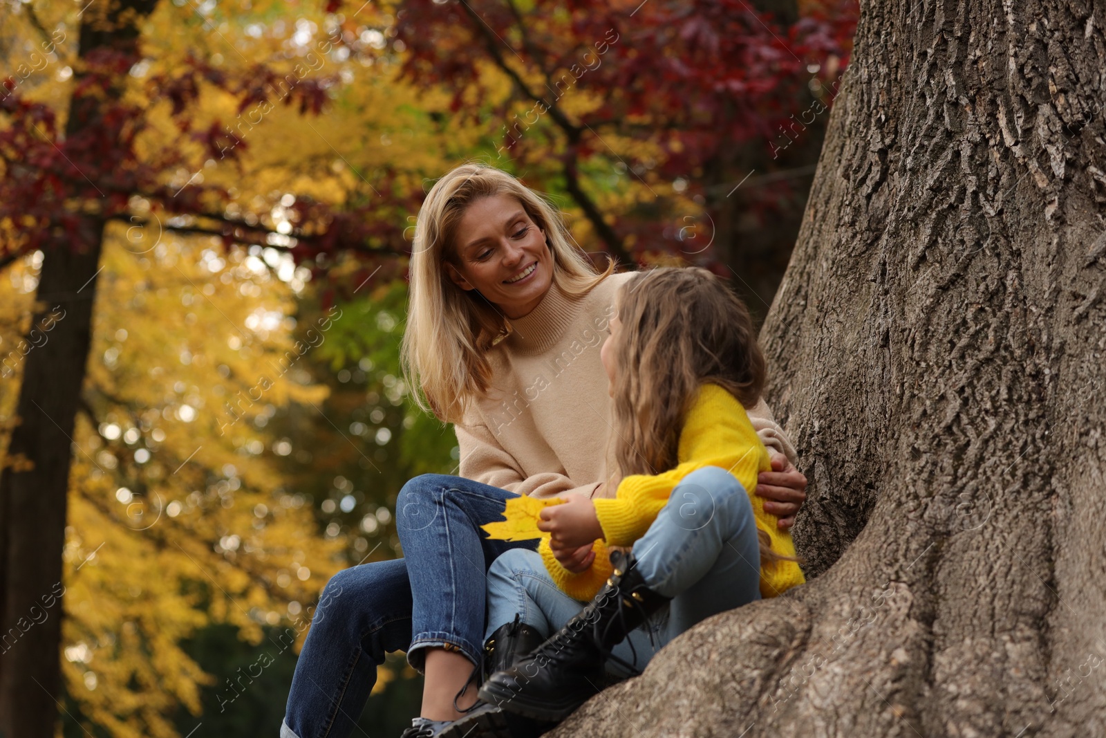 Photo of Happy mother spending time together with her daughter in autumn park, low angle view