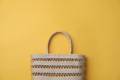 Stylish straw bag on yellow background, top view with space for text. Summer accessory