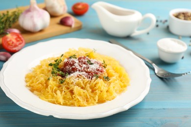 Photo of Tasty spaghetti squash with tomato sauce, cheese and thyme served on light blue wooden table