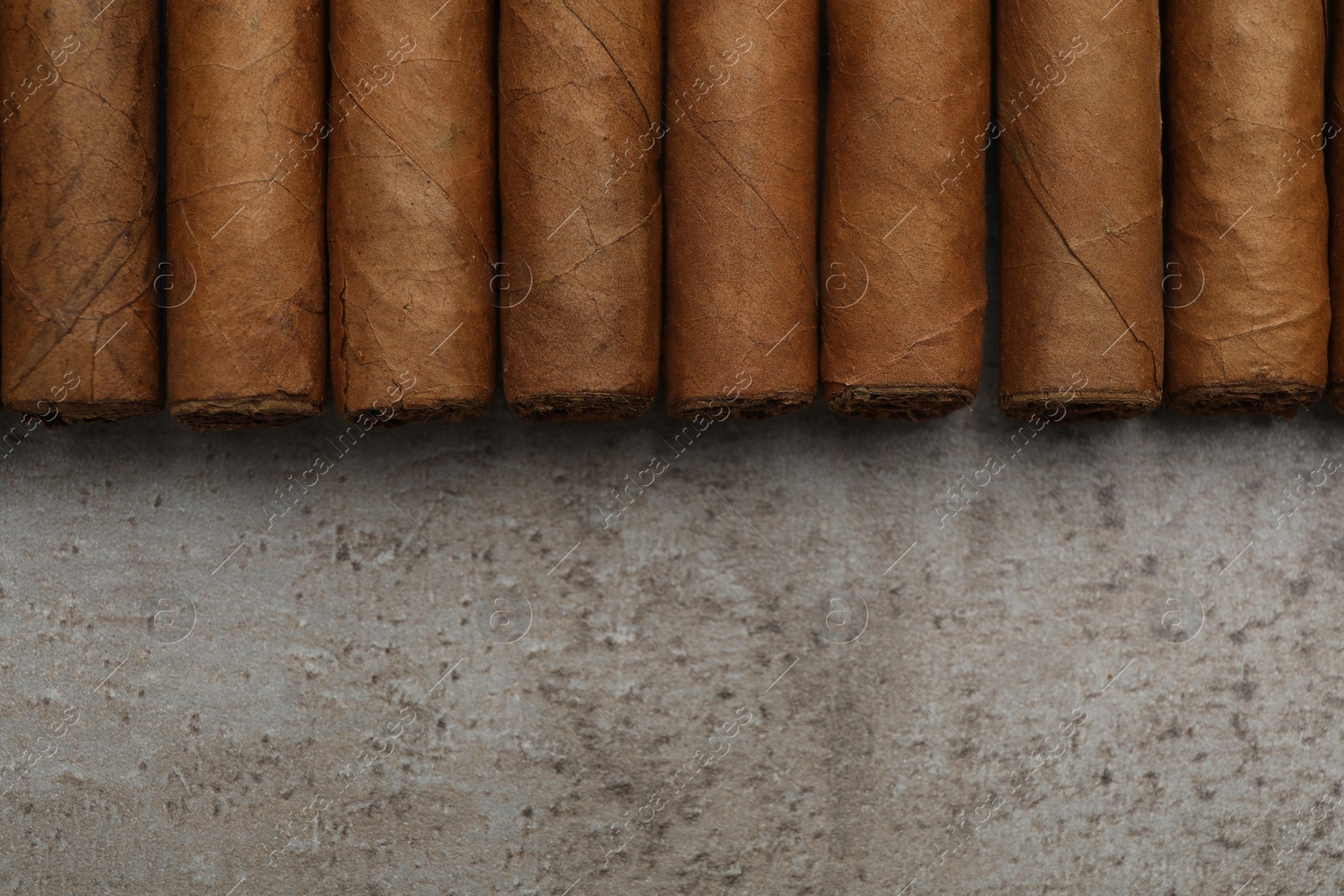 Photo of Many expensive cigars on grey table, flat lay. Space for text