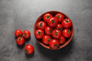 Bowl with ripe cherry tomatoes on color background, top view