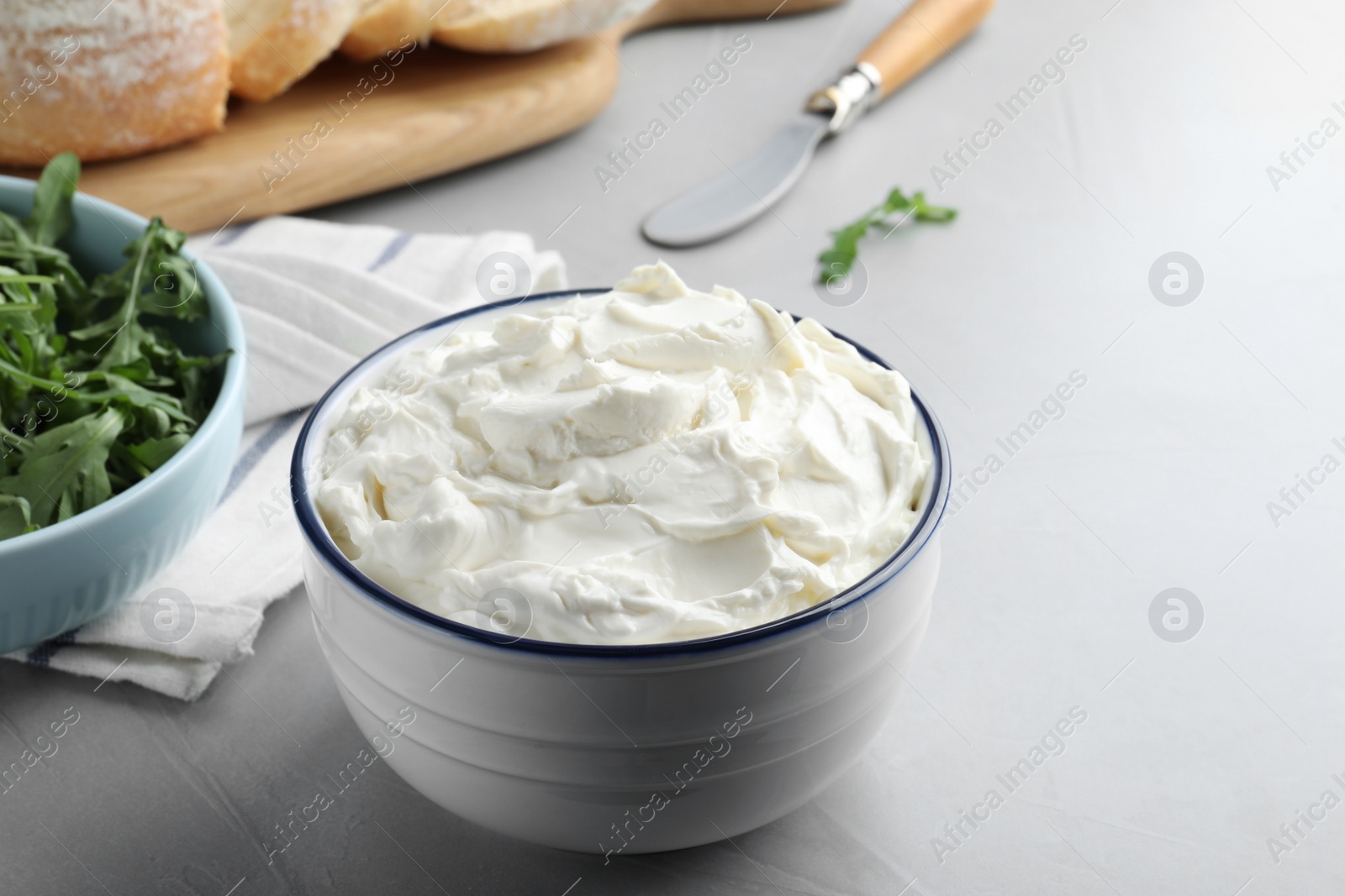 Photo of Bowl of tasty cream cheese on grey table