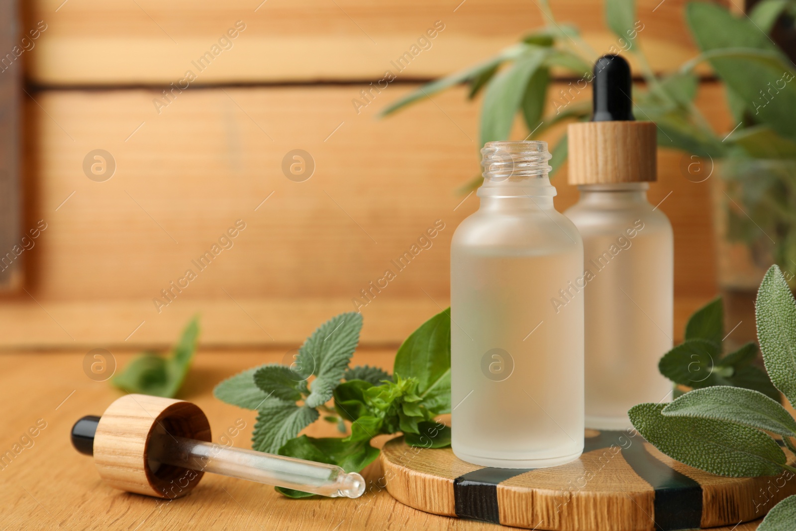 Photo of Bottles of essential oils and fresh herbs on wooden table