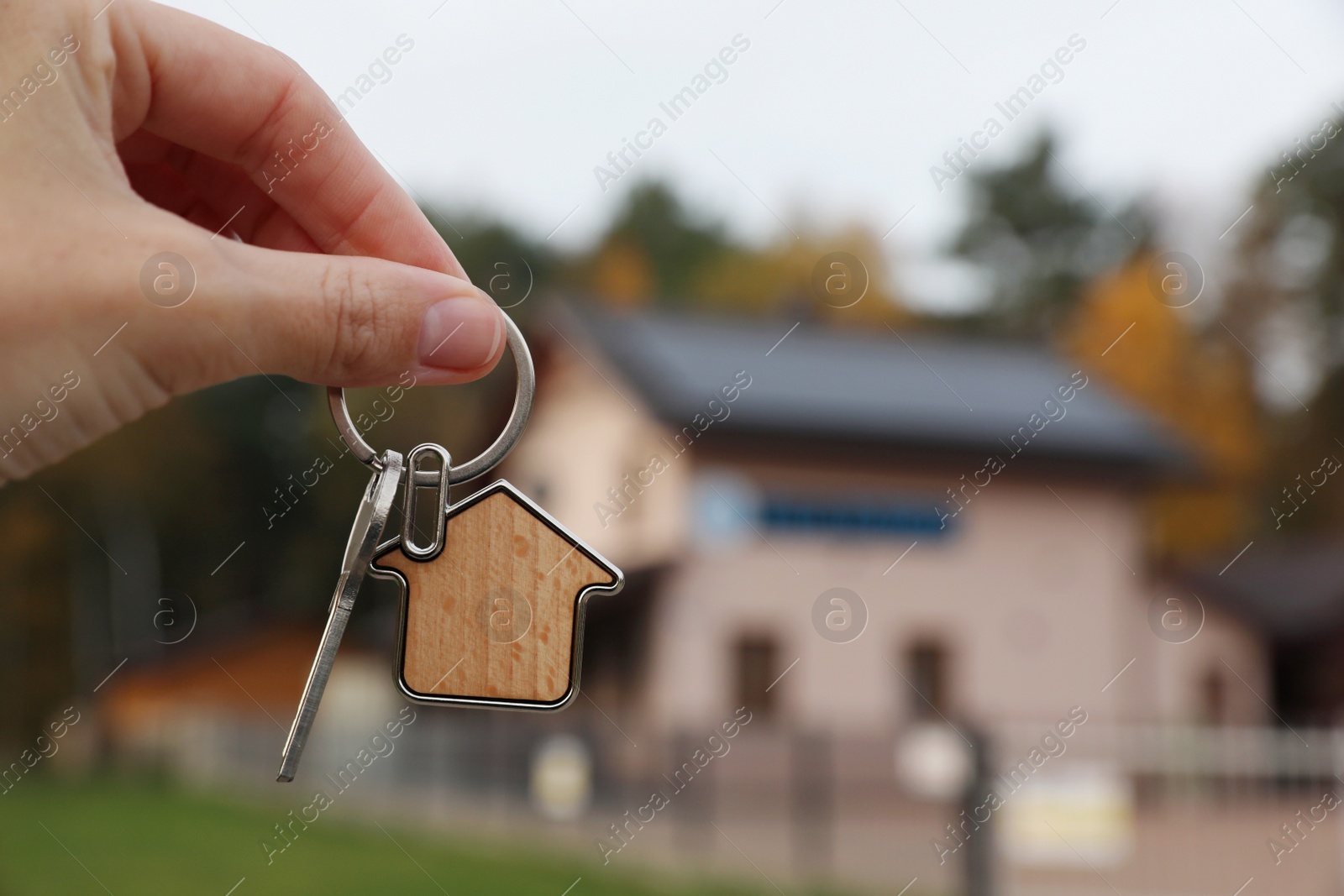 Photo of Woman holding house keys outdoors, closeup with space for text. Real estate agent