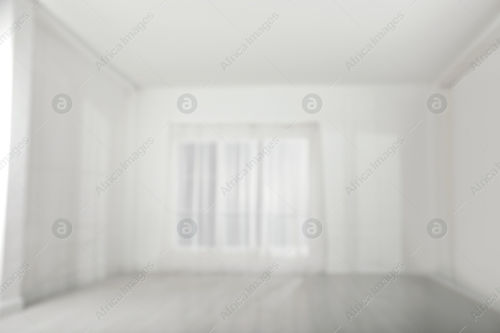 Photo of Empty room with white walls and large window, blurred view