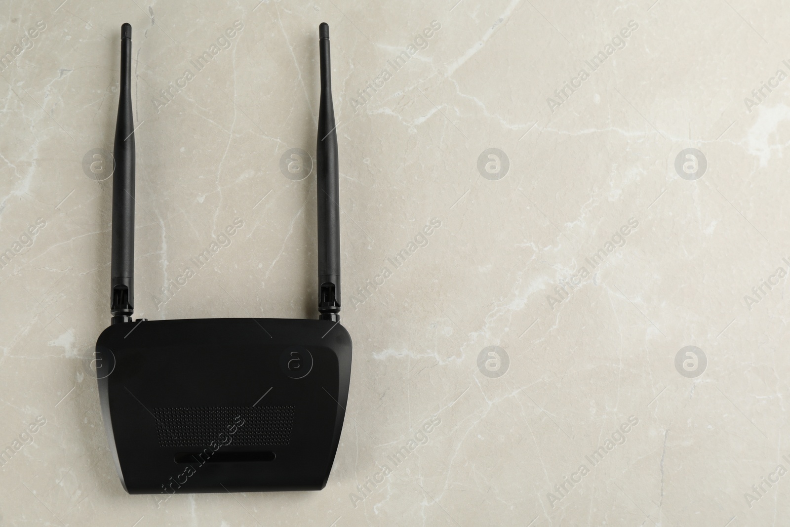 Photo of Modern Wi-Fi router on light grey marble background, top view. Space for text