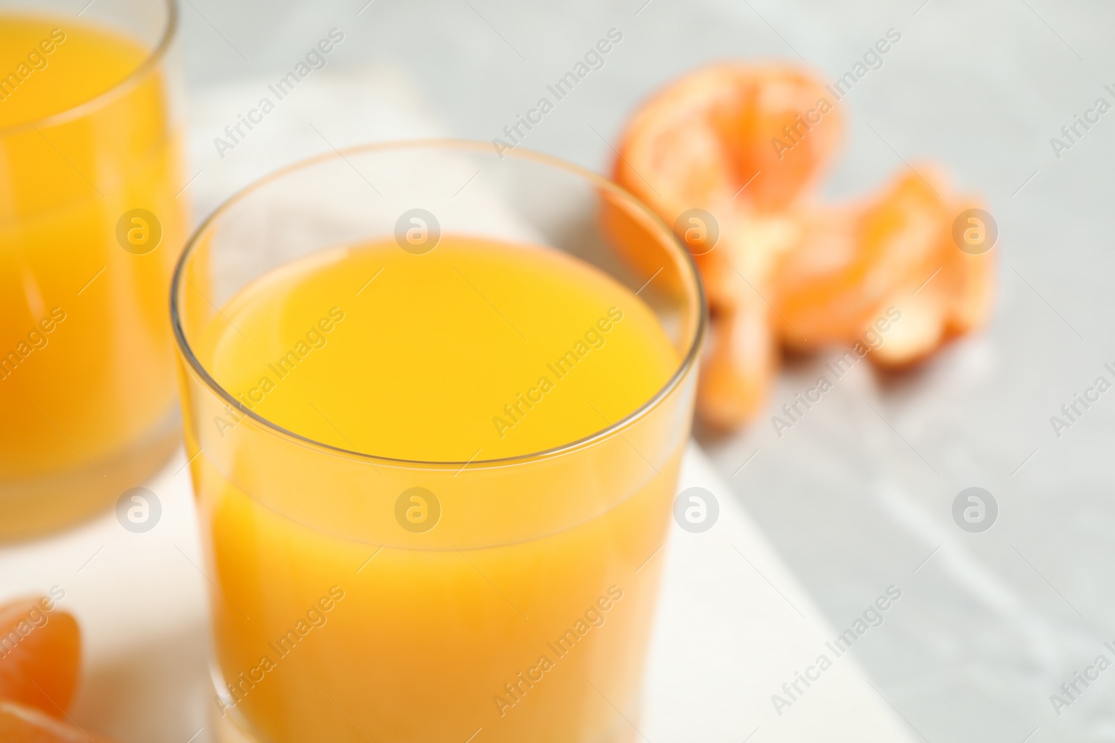 Photo of Glass of fresh tangerine juice and fruits on table, closeup