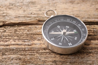 Photo of One compass on wooden table, space for text. Tourist equipment