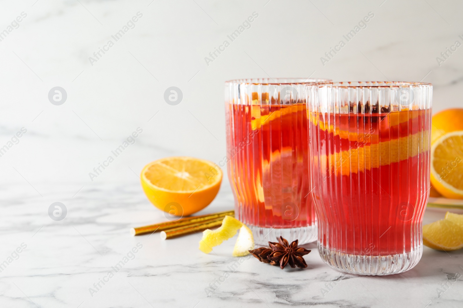 Photo of Aromatic punch drink and ingredients on white marble table. Space for text