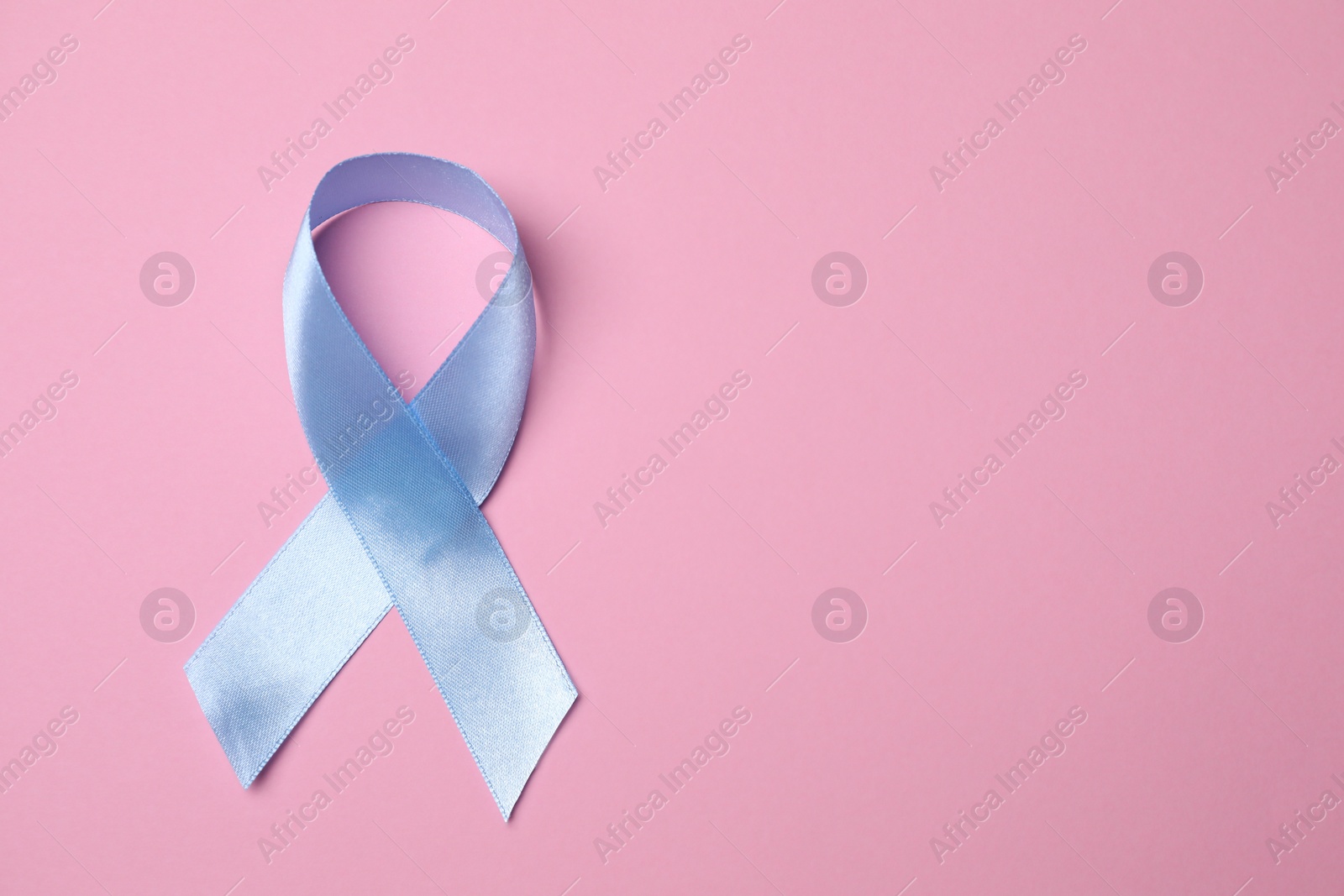 Photo of International Psoriasis Day. Light blue ribbon as symbol of support on pink background, top view. Space for text