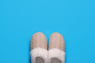 Pair of beautiful soft slippers on light blue background, top view. Space for text