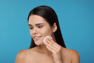 Photo of Young woman with cotton pad on light blue background