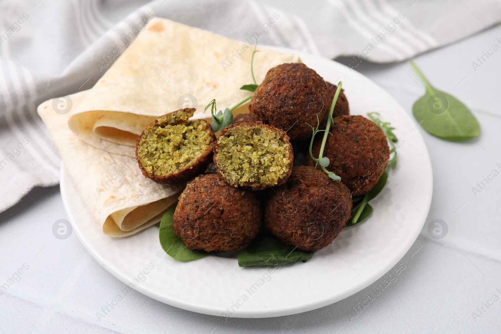 Photo of Delicious falafel balls, herbs and lavash on white table