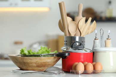 Photo of Set of cooking utensils and products on white table against blurred background