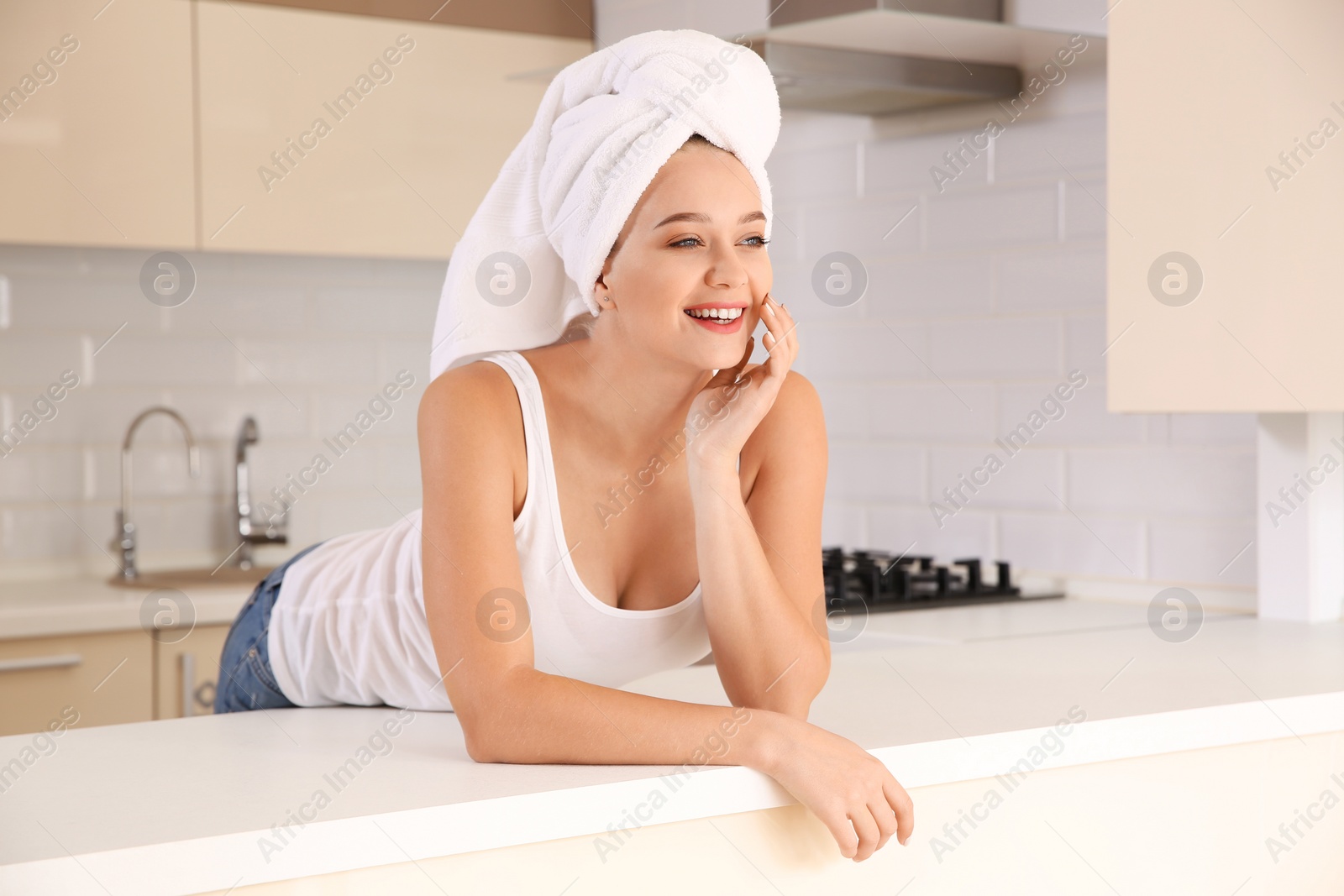 Photo of Beautiful woman with towel on head in kitchen at home