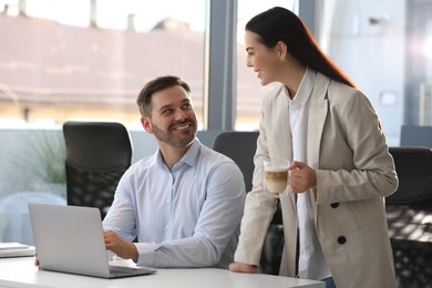 Photo of Colleagues working on laptop at desk in office