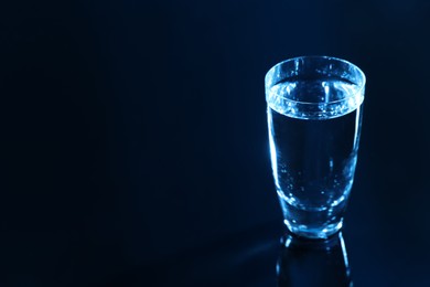 Photo of Glass of vodka on dark table, space for text