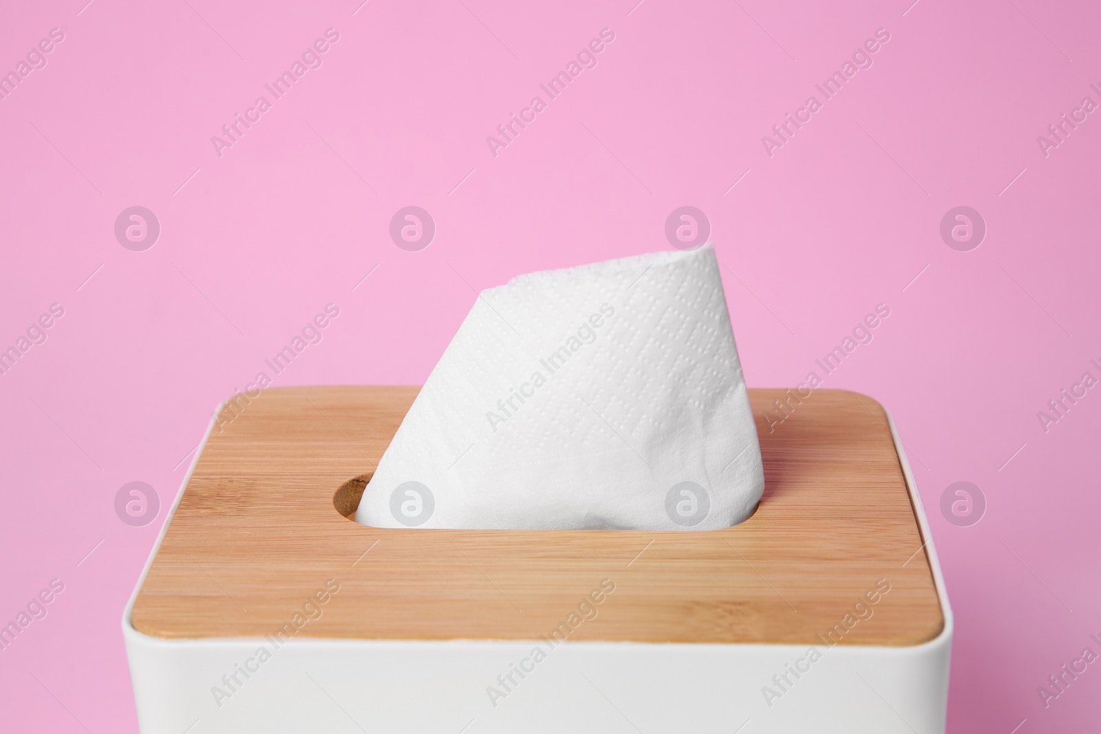 Photo of Holder with paper tissues on pink background, closeup