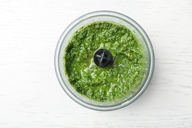 Photo of Homemade basil pesto sauce in blender container on white background, top view