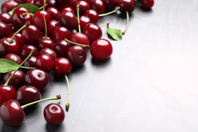 Photo of Sweet juicy cherries with leaves on light table. Space for text