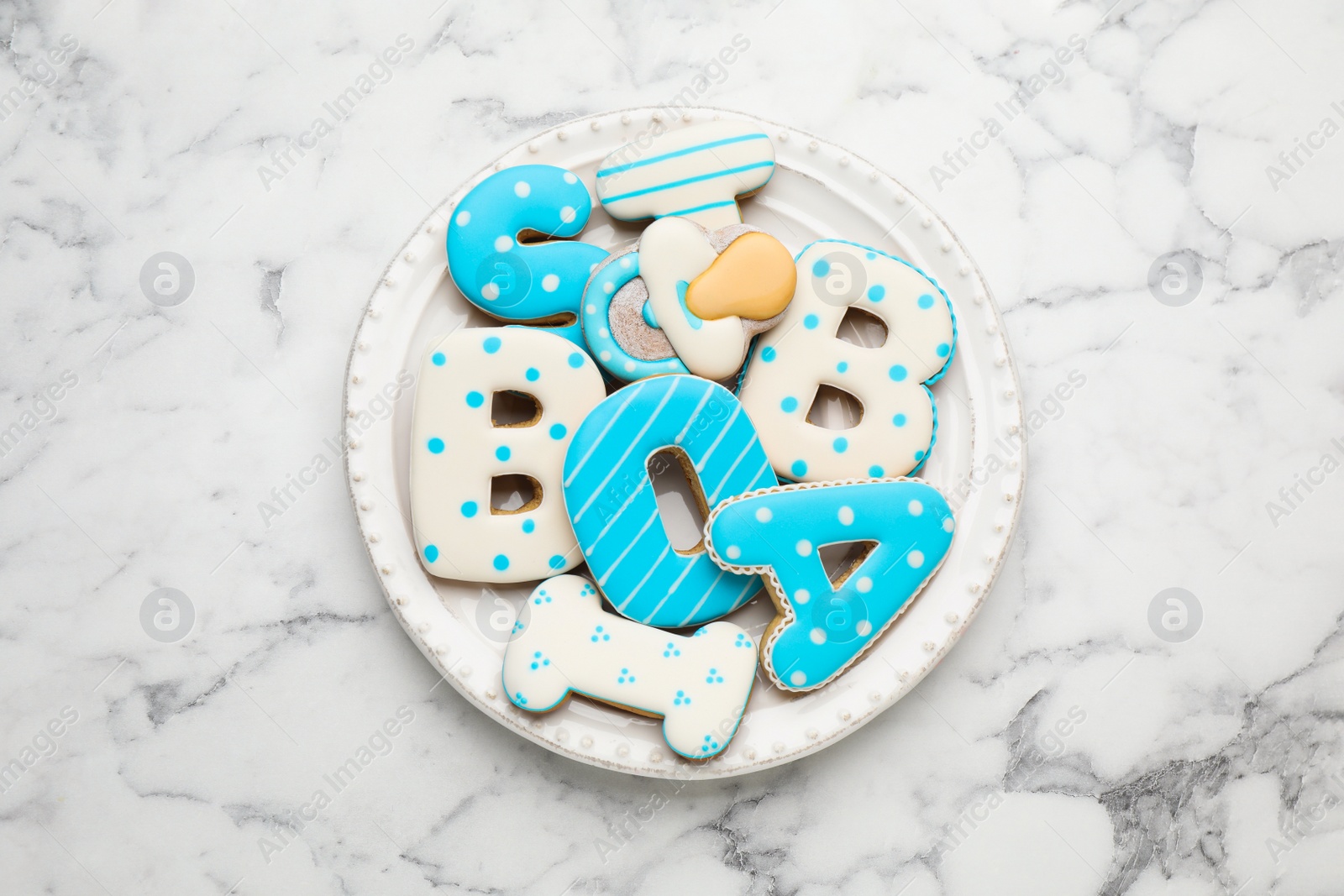 Photo of Plate of baby shower cookies on white marble table, top view