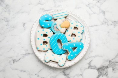 Plate of baby shower cookies on white marble table, top view