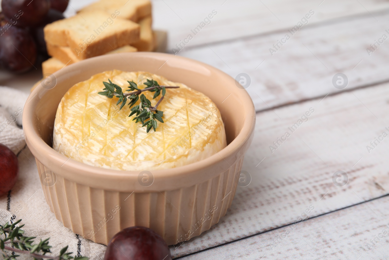 Photo of Tasty baked camembert and thyme in bowl on table, closeup