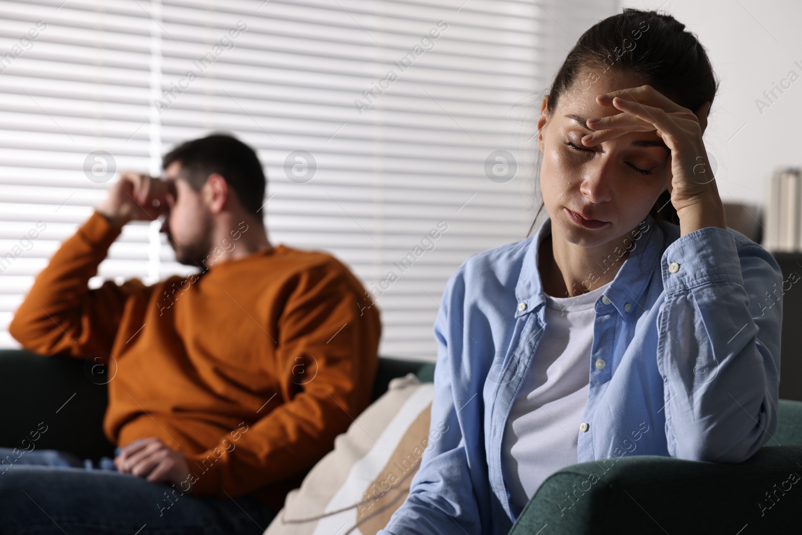 Photo of Offended couple ignoring each other after quarrel indoors, selective focus. Relationship problems