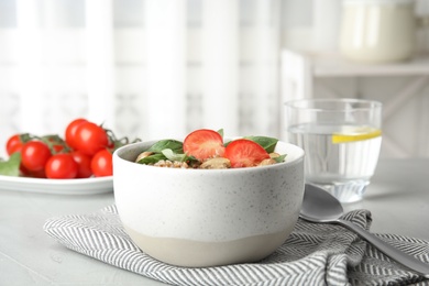 Photo of Delicious buckwheat porridge with mushrooms and tomato on table indoors