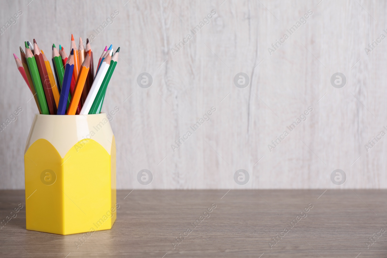 Photo of Many different pencils in holder on wooden table, space for text