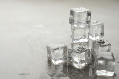 Photo of Crystal clear ice cubes with water drops on grey table, closeup. Space for text