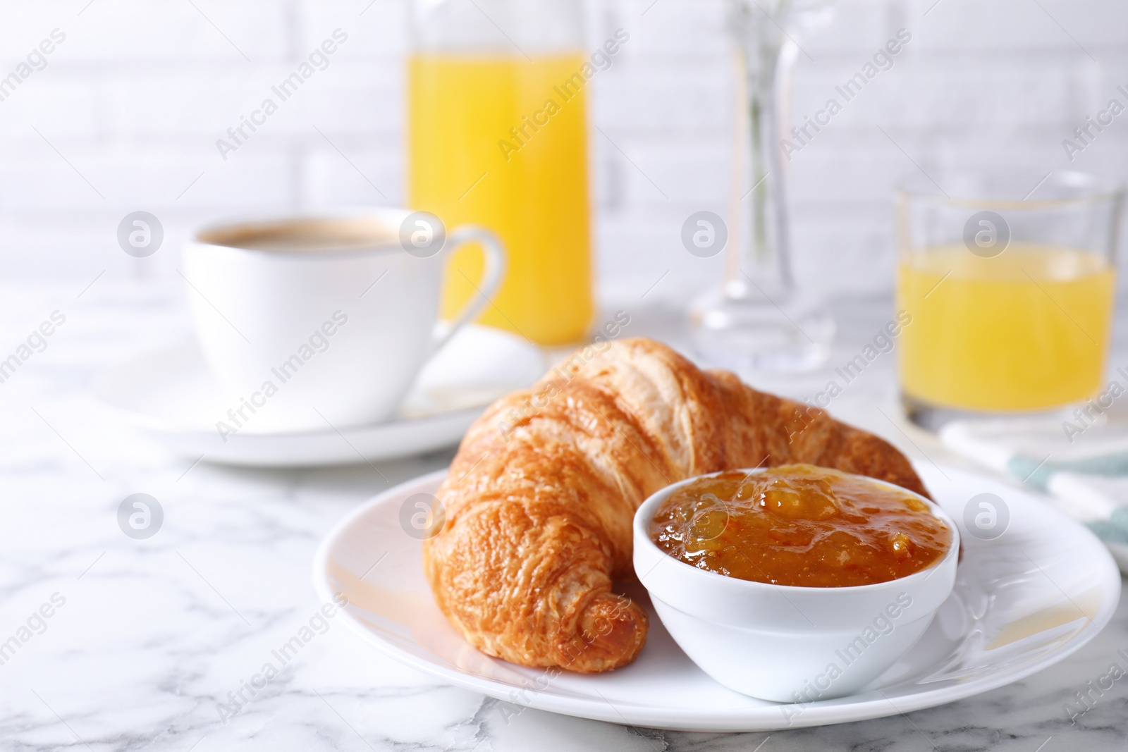 Photo of Tasty breakfast. Fresh croissant and jam on white marble table