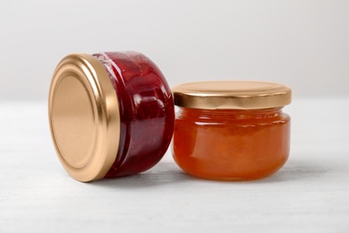 Two jars with tasty sweet jam on white wooden table