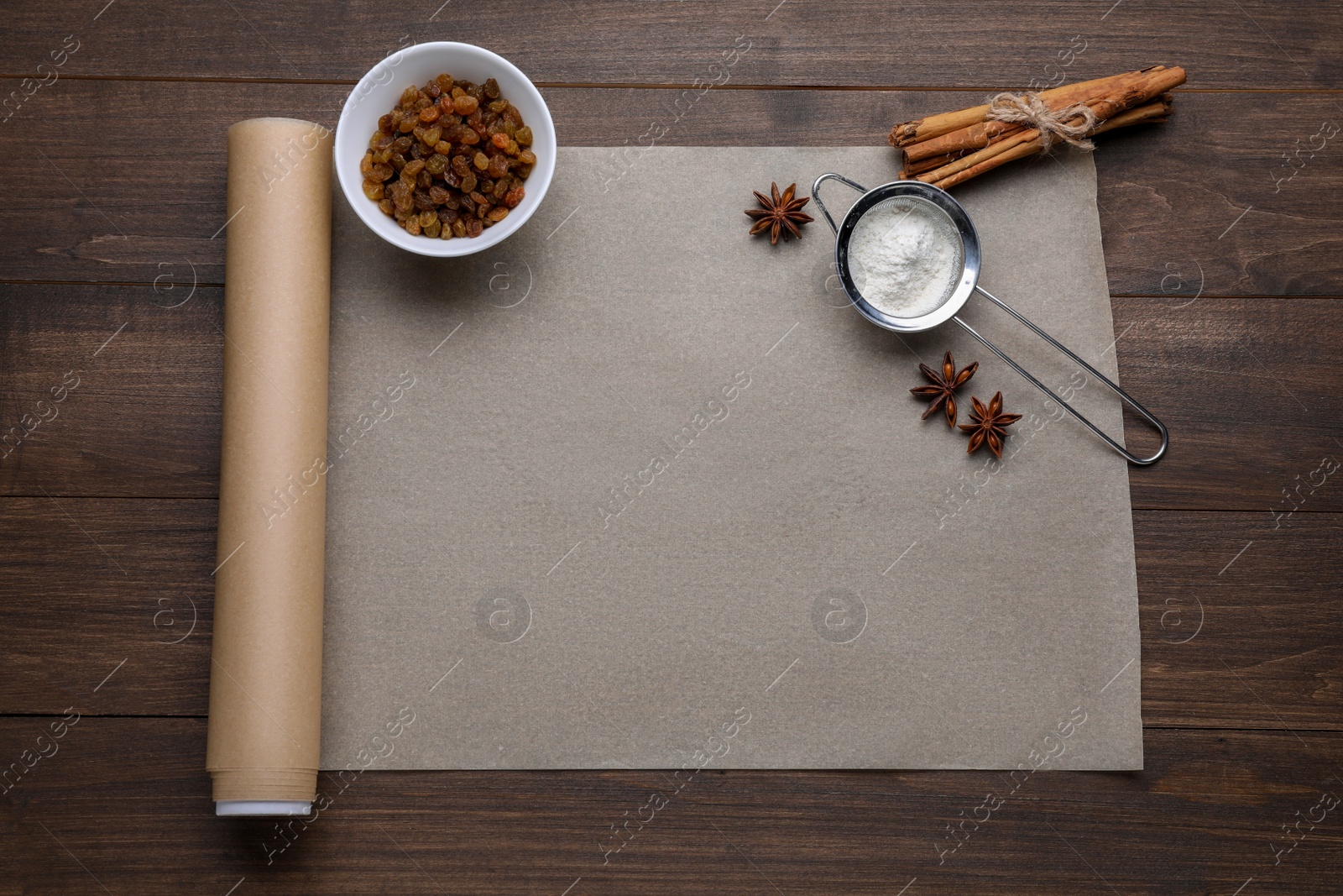 Photo of Baking parchment paper and different ingredients on wooden table, flat lay. Space for text