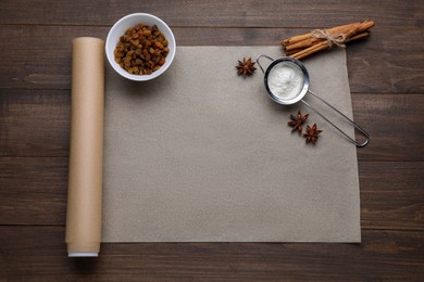 Photo of Baking parchment paper and different ingredients on wooden table, flat lay. Space for text