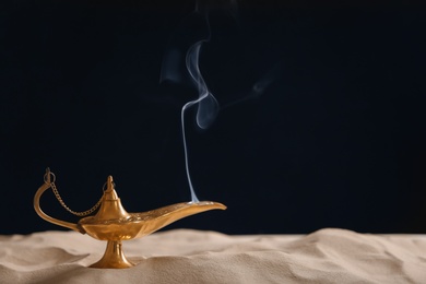 Photo of Aladdin lamp of wishes on sand against black background