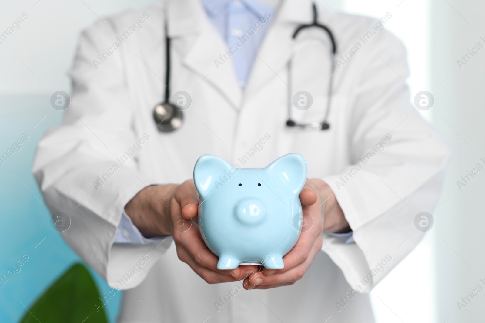 Photo of Doctor with piggy bank in hospital, closeup