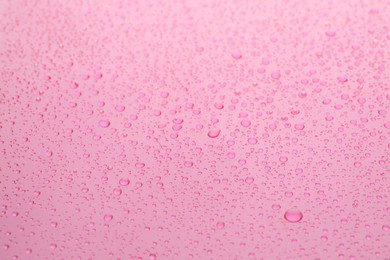 Water drops on pink background, closeup view