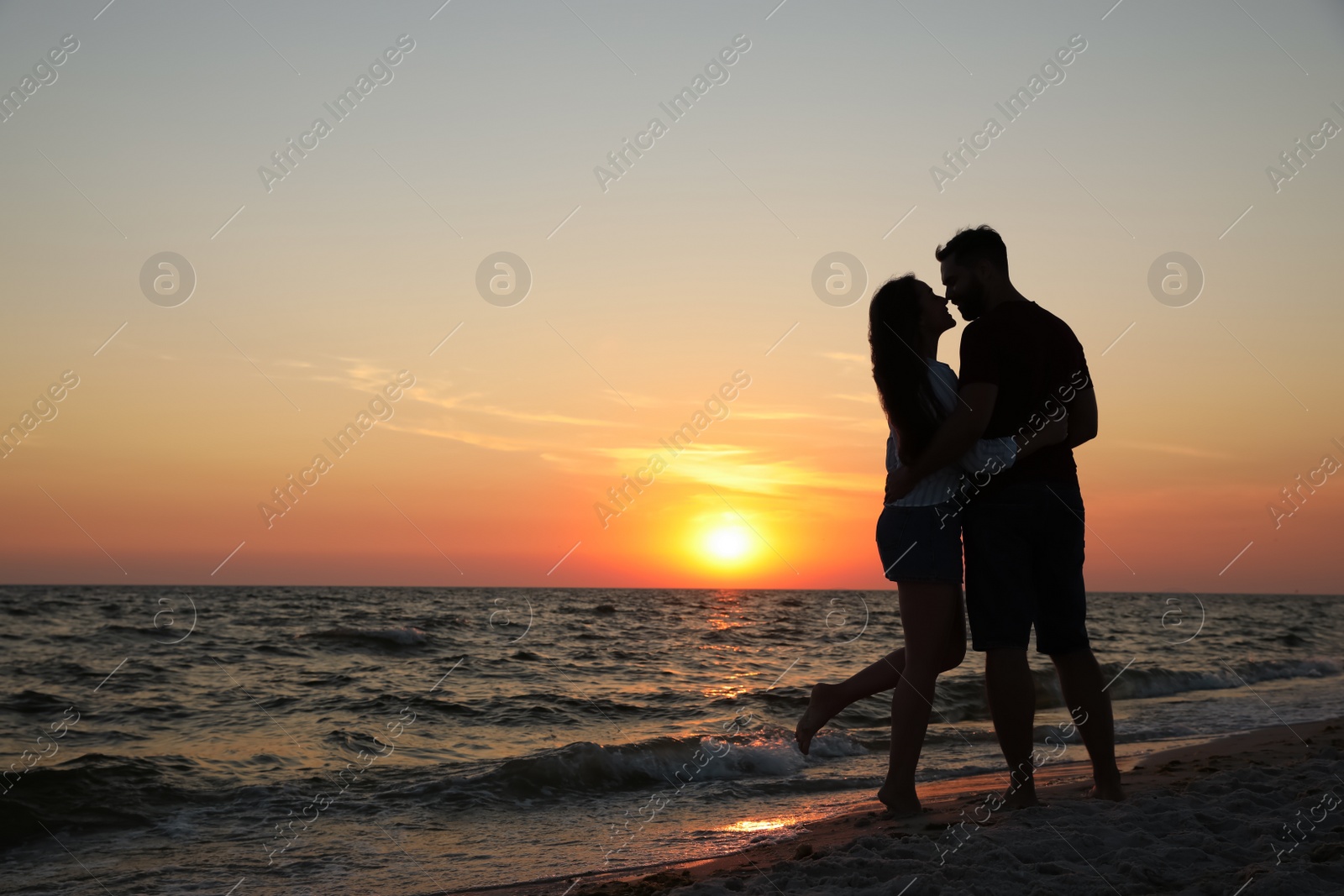 Photo of Couple spending time together on beach at sunset