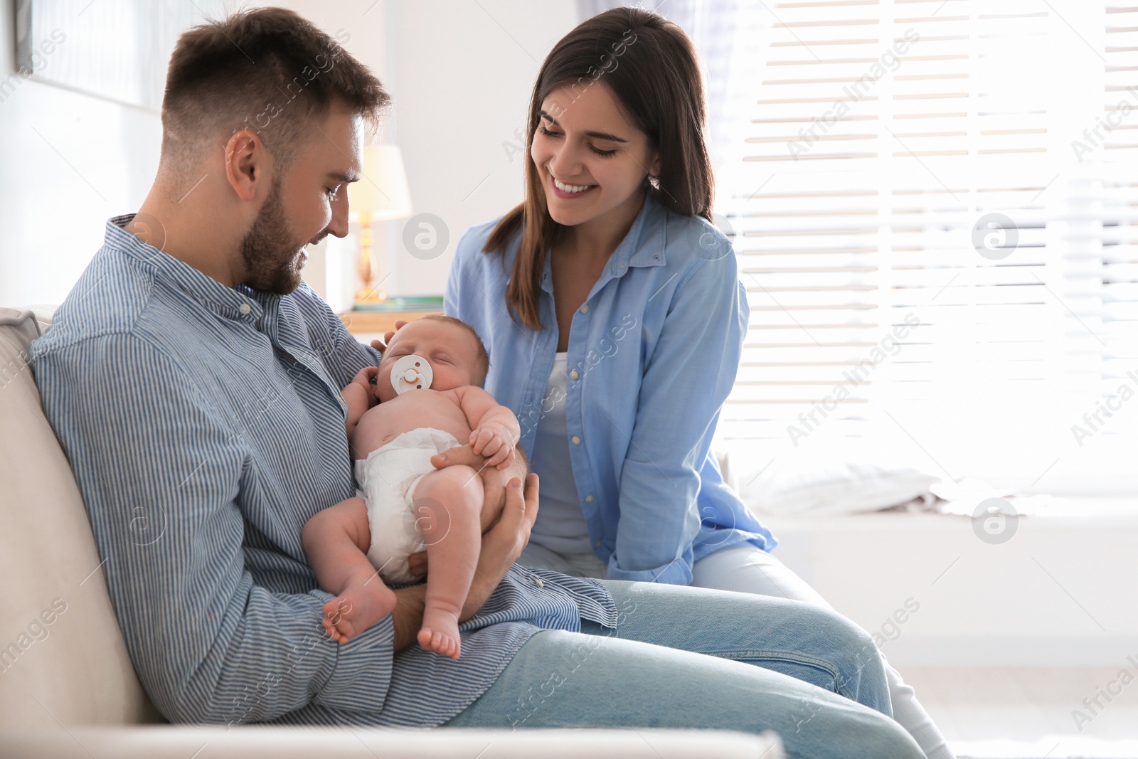 Photo of Happy couple with their newborn baby at home