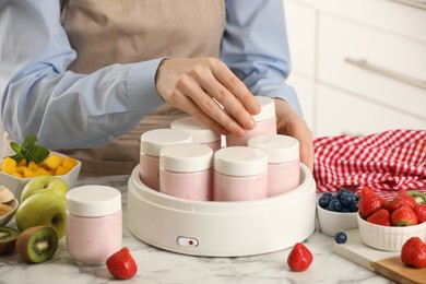 Photo of Woman making tasty yogurt at white marble table indoors, closeup