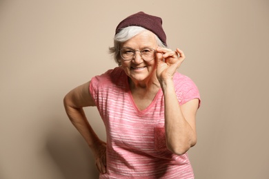 Portrait of elderly woman in hipster outfit on color background