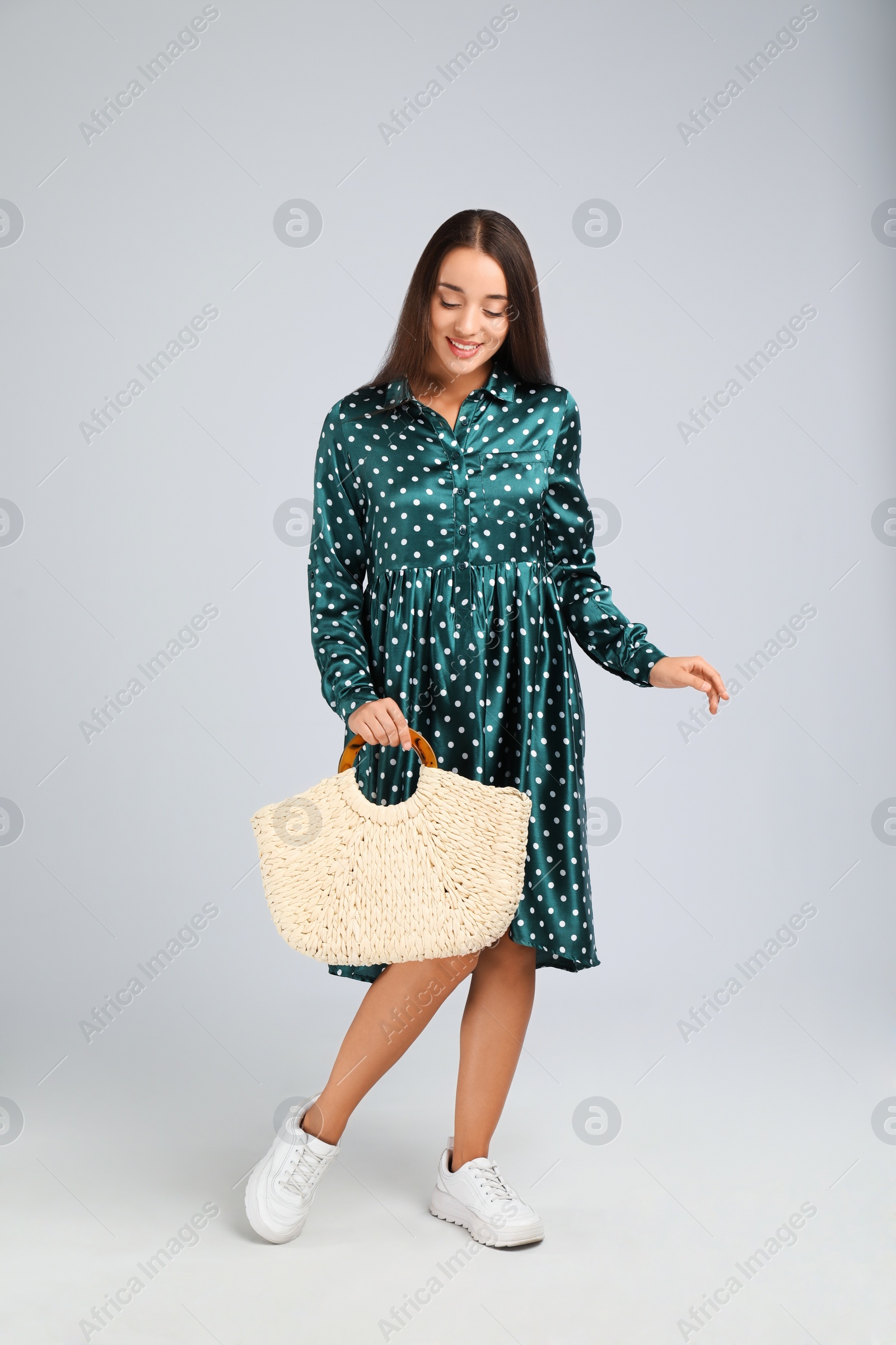 Photo of Young woman with stylish straw bag on light grey background