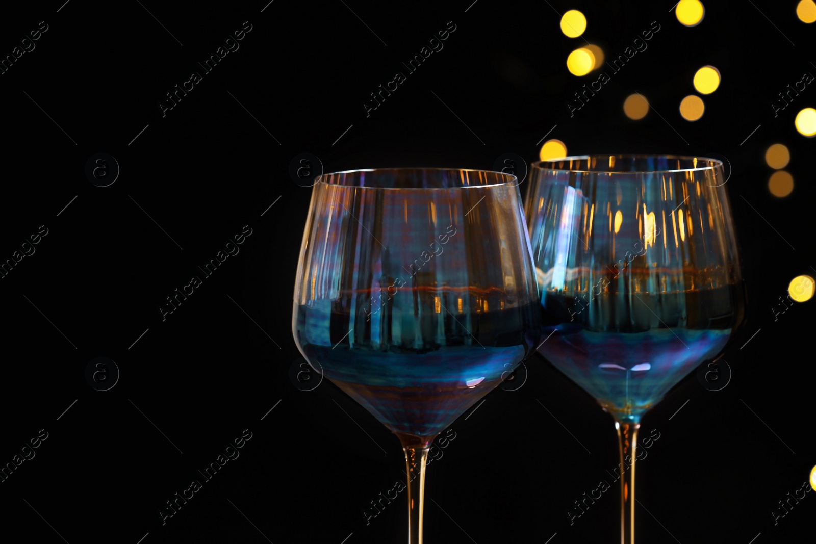 Photo of Glasses of red wine against blurred lights, closeup