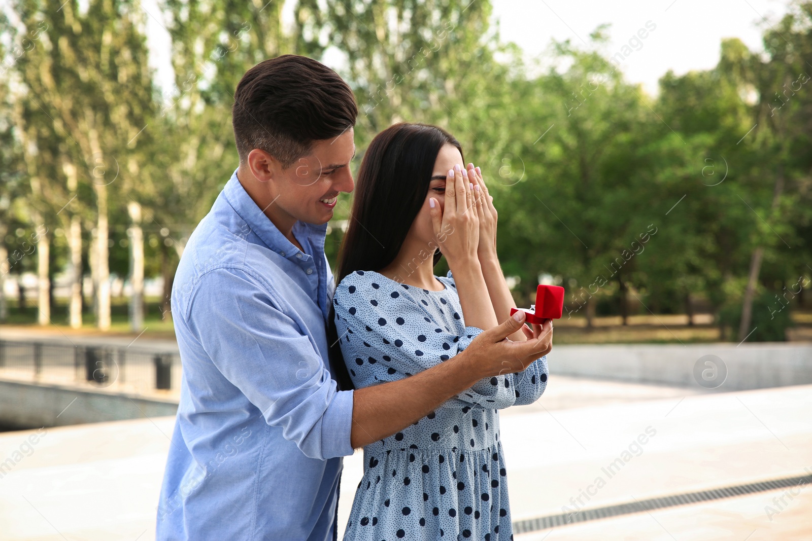 Photo of Man with engagement ring making proposal to his girlfriend outdoors