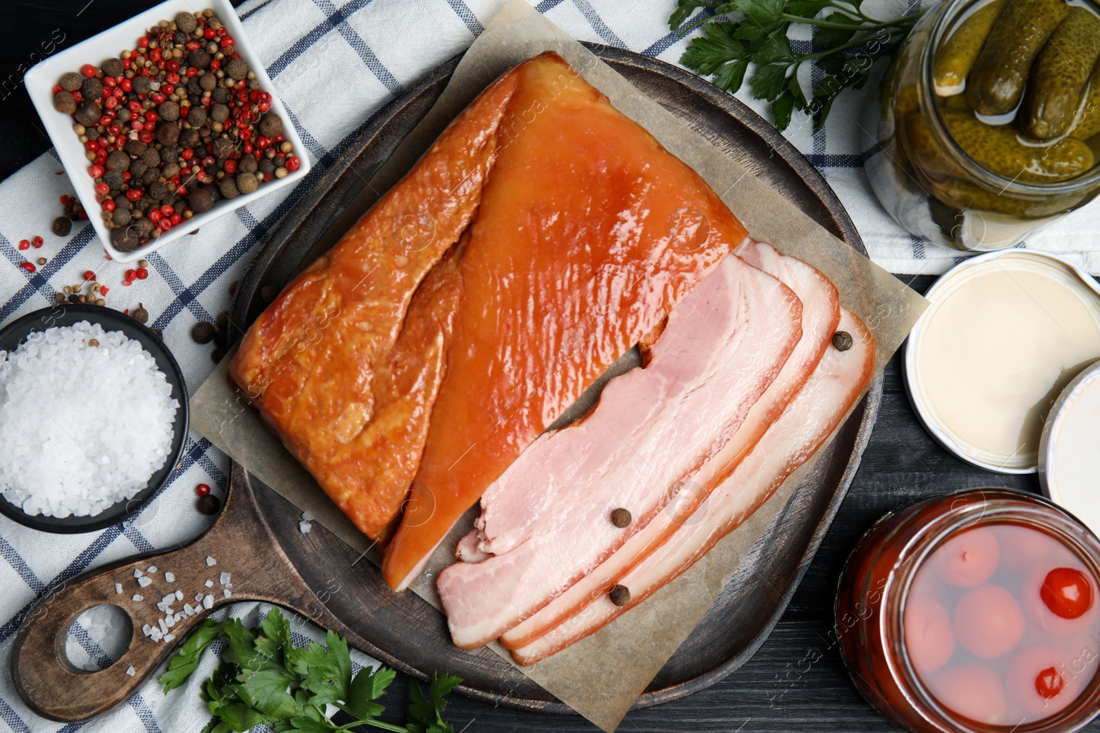 Photo of Flat lay composition with delicious smoked bacon on black wooden table