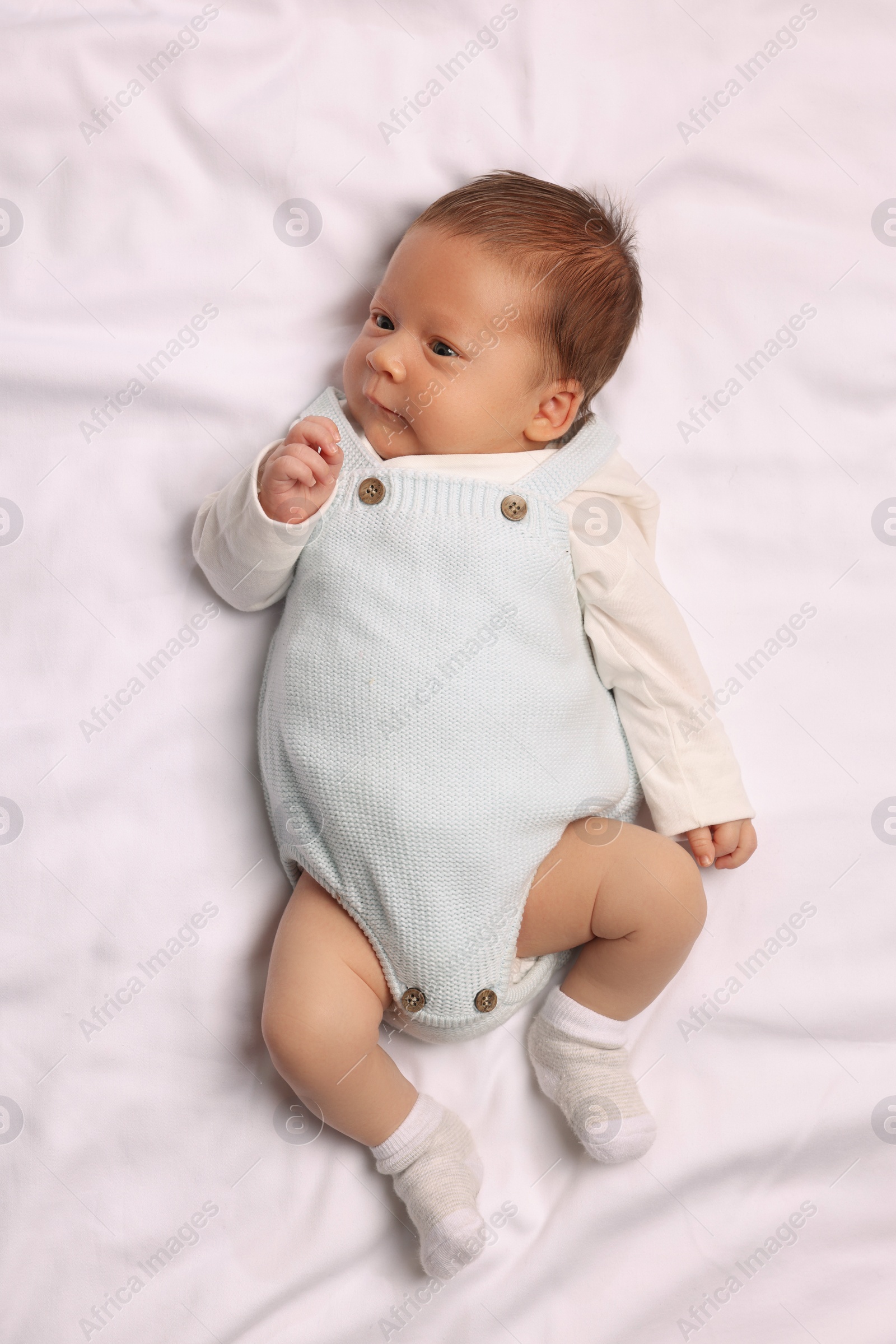 Photo of Cute newborn baby lying on white blanket, top view