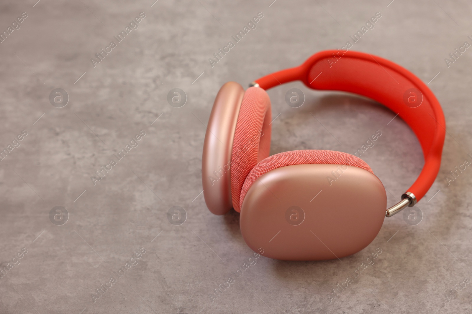 Photo of Stylish pink headphones on light grey table, closeup. Space for text