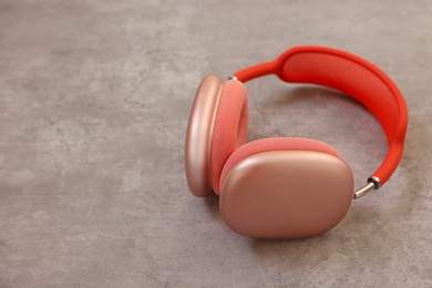 Stylish pink headphones on light grey table, closeup. Space for text